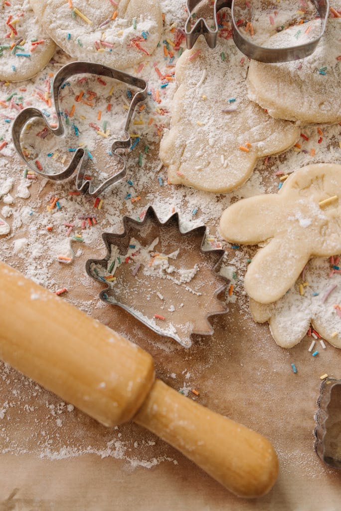 Closeup of raw cookie dough with cutters, flour, and sprinkles.