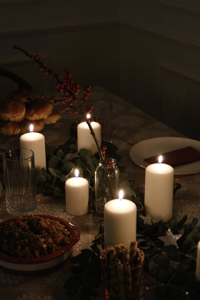 Elegant candlelit dinner table set with festive holiday decor, creating a warm ambiance.