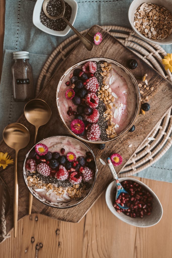 Top view of nutritious smoothie bowls with berries, chia seeds, and oats on a wooden table.